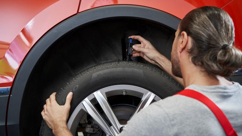 Ein Servicemitarbeiter vom Volkswagen Economy Service misst die Profiltiefe eines Reifens