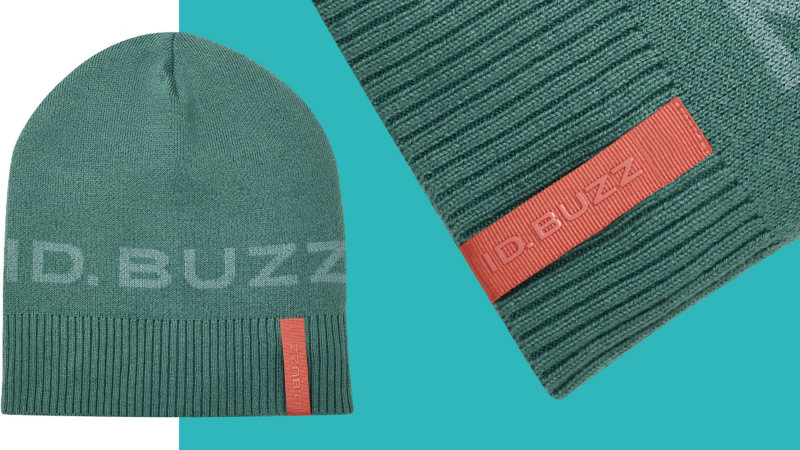 Petrolfarbene Strickmütze mit „ID. Buzz“-Schriftzug auf dem Stoff und am orangefarbenen Label