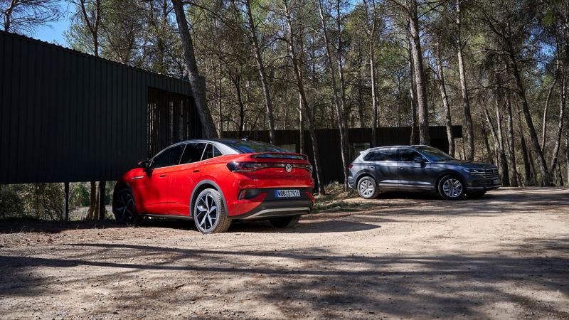 Dos coches VW nuevos aparcados junto a una casa en el bosque 