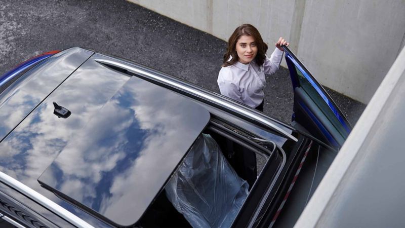 Ripresa dall'alto di una ragazza appoggiata allo sportello aperto di un veicolo Volkswagen.