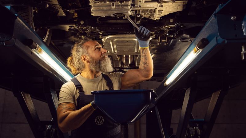 Un collaborateur de service VW effectue une vidange d’huile sur une VW, dans le cadre d’un entretien flexible ou d’un entretien fixe – vidange d’huile VW