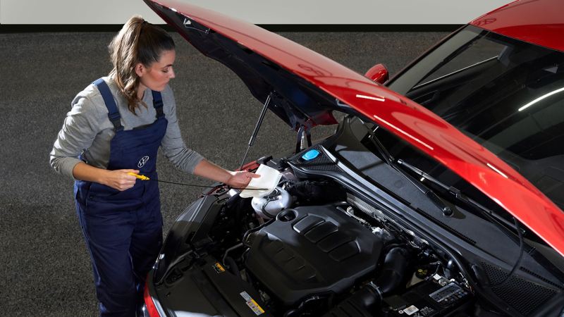 A VW employee changes the engine oil of a VW car – Oil Service