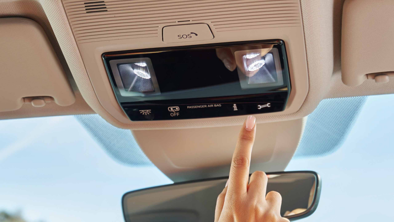 Jemand drückt die Taste Online-Pannenruf in einem VW Auto
