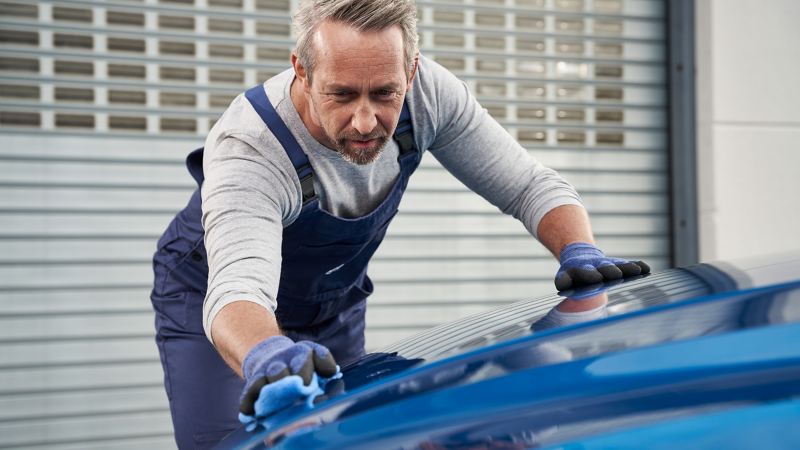 Un agente de servicio de Volkswagen abrillantando la pintura de un coche