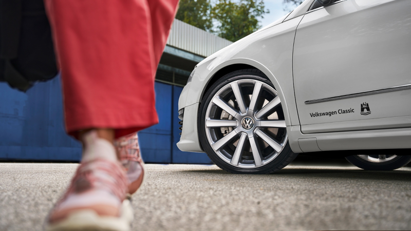 Gros plan sur une roue avec jante d’une VW Passat B6, les pieds d’une personne sont visibles au premier plan