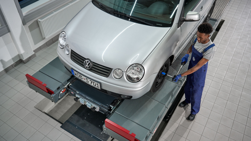 Un empleado del servicio Volkswagen trabajando en la rueda delantera de un Volkswagen Polo 4