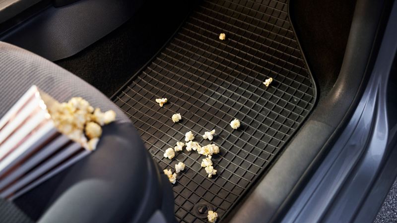 Overturned popcorn bag on front passenger seat, spilt popcorn on VW Accessories floor mat – accessories for previous models