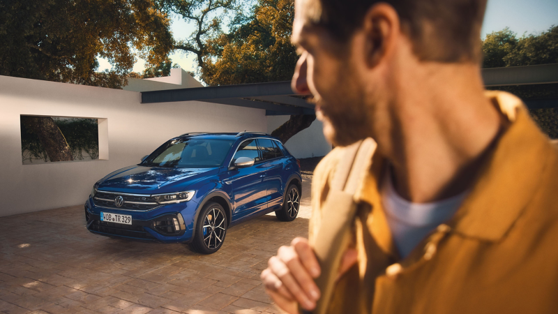 Un homme regarde sa VW R T-Roc R garée dans une cour