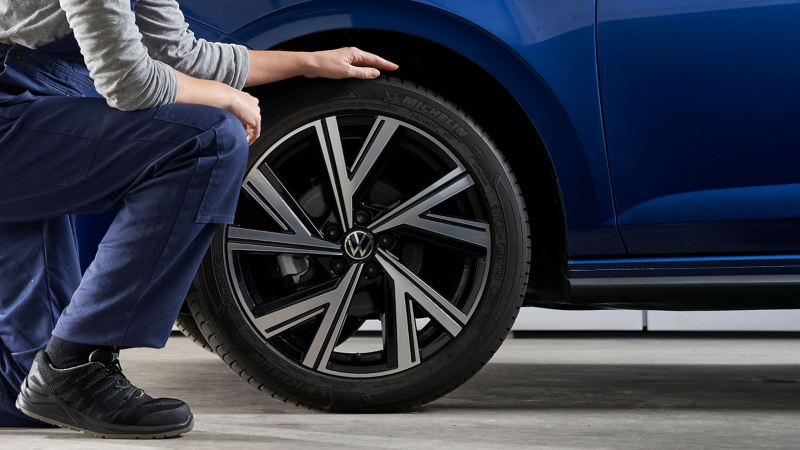 Eine Servicemitarbeiterin kontrolliert den Reifen eines VW