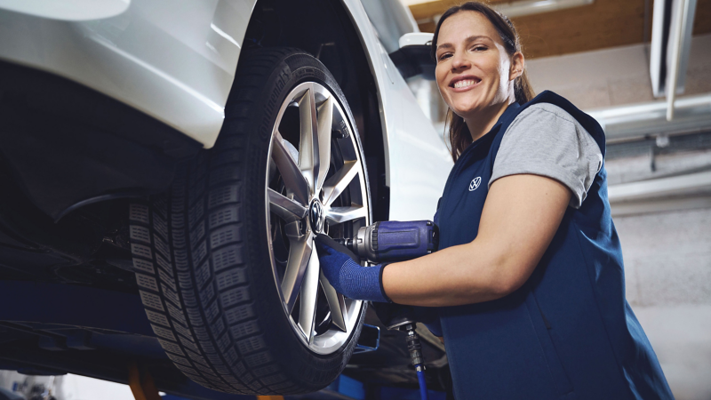 VW Servicemitarbeiterin prüft Bremsen am Auto