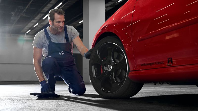 Ein VW Servicemitarbeiter prüft in der Werkstatt die Reifen eines Golf 5