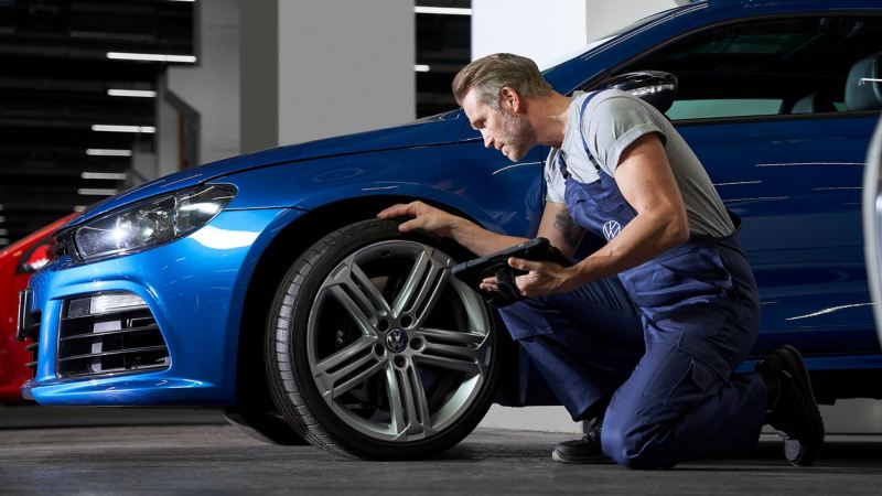 Ein VW Servicemitarbeiter prüft die Reifen eines Scirocco 3 in der Werkstatt