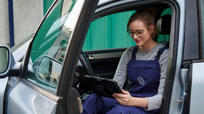 Una empleada del servicio técnico de VW revisa su tablet en un coche VW 