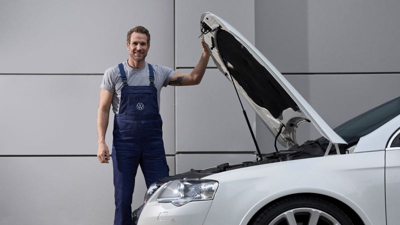 Un empleado del servicio técnico de VW junto a un Passat con el capó abierto