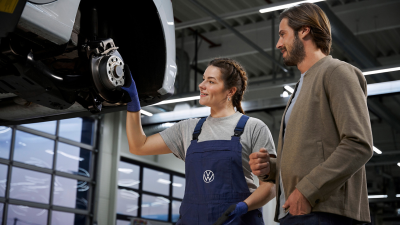 VW Servicemitarbeiterin und Kunde am Auto – Service in der Werkstatt