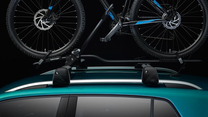 Une VW T-Cross équipée d’un porte-vélos des accessoires VW avec un vélo sur le toit du véhicule