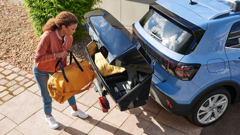 Een vrouw laadt de achterbak van VW-accessoires die bevestigd is op een VW T-Cross