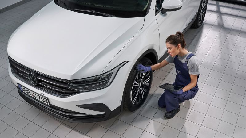 VW service employee inspects tyre of a VW Tiguan 2