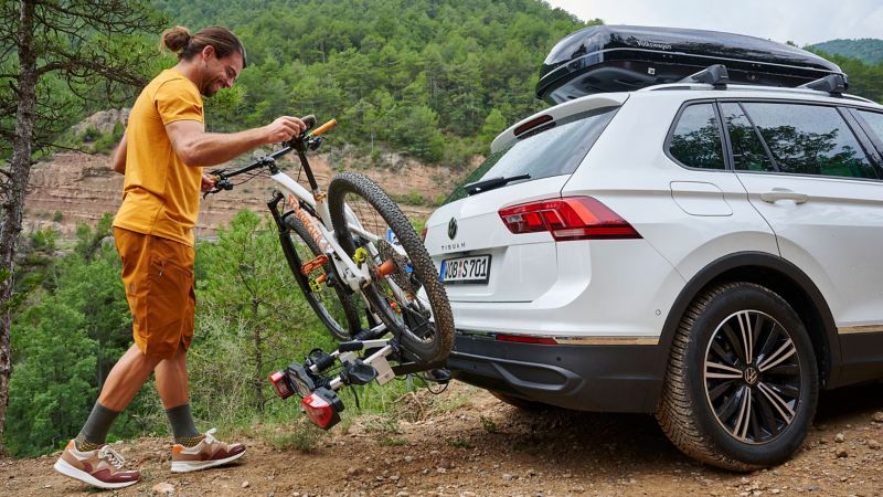 Man zet een fiets vast op de fietsendrager van VW-accessoires op een VW Tiguan