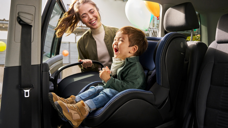 Un bebé en el asiento trasero con una sillita de niño en un Volkswagen Touran