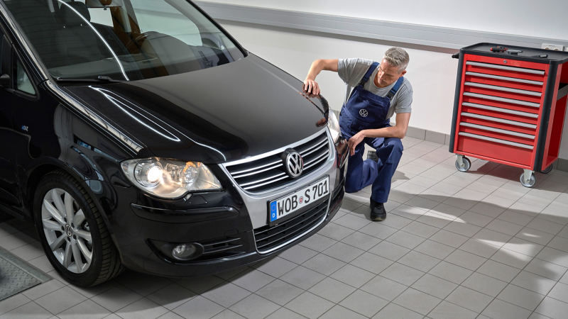 Un empleado del servicio técnico de Volkswagen revisando un Volkswagen Touran 1