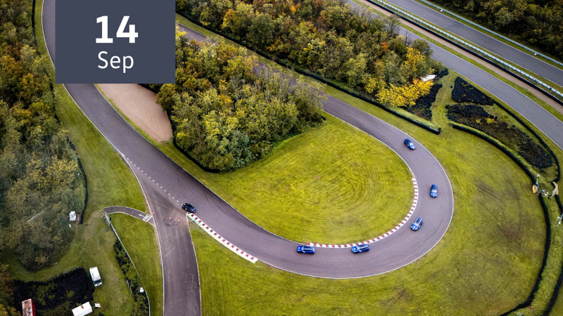 Vogelperspektive zeigt Trainingsfahrzeuge der Driving Experience bei einer Kurvenfahrt auf einer Rennstrecke