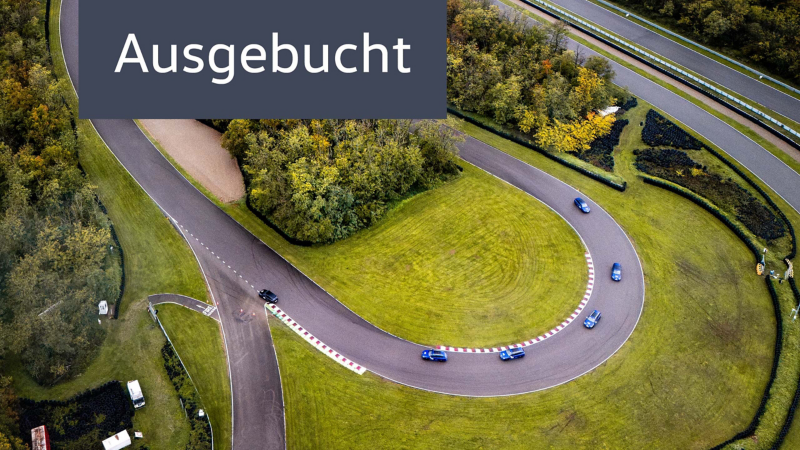 Vogelperspektive zeigt Trainingsfahrzeuge der Driving Experience bei einer Kurvenfahrt auf einer Rennstrecke