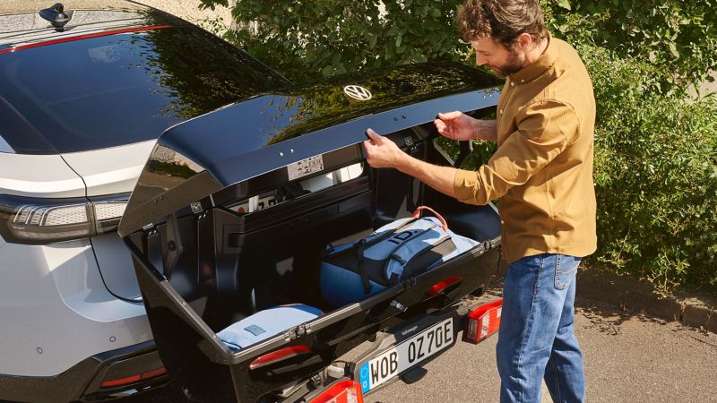Mann verstaut Gepäck in Heckbox eines VW ID.7