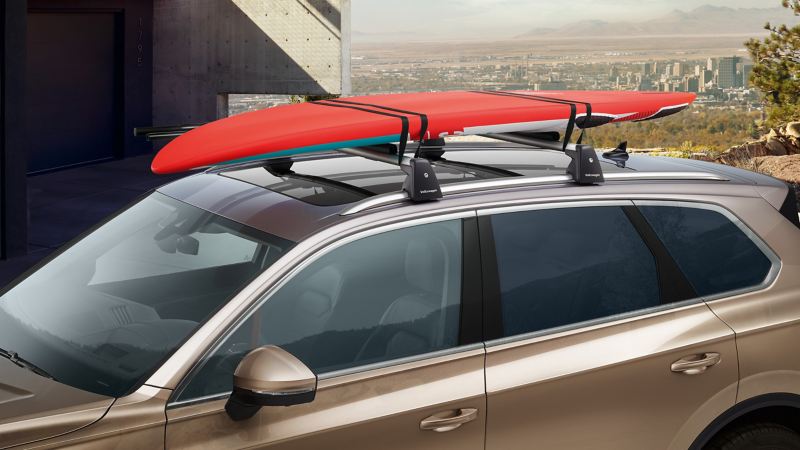 Een VW Touareg met een surfplank erop wordt voor een huis geparkeerd