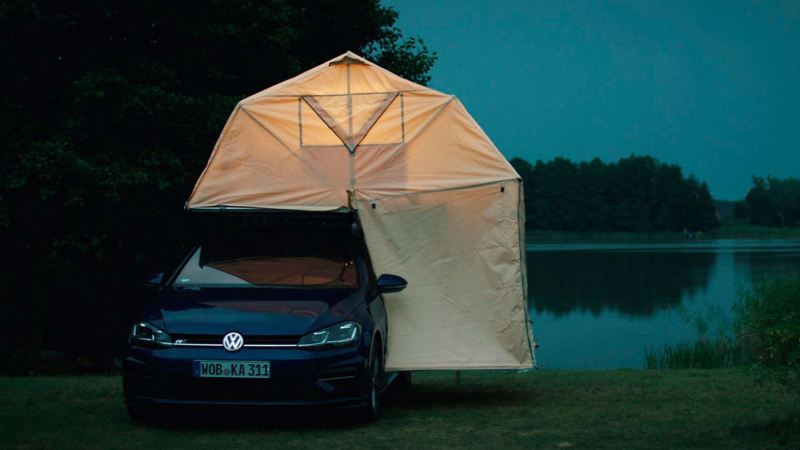 A VW model with car tent at a lake