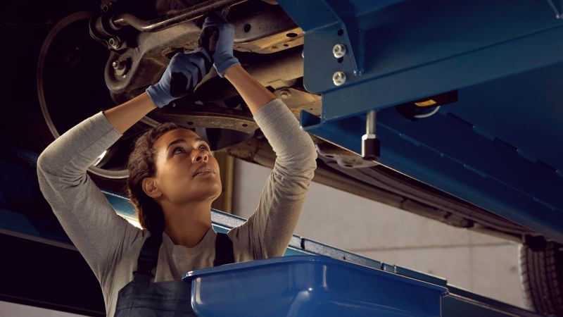 Mechanikerin erledigt Arbeiten am VW – Wartung & Inspektion