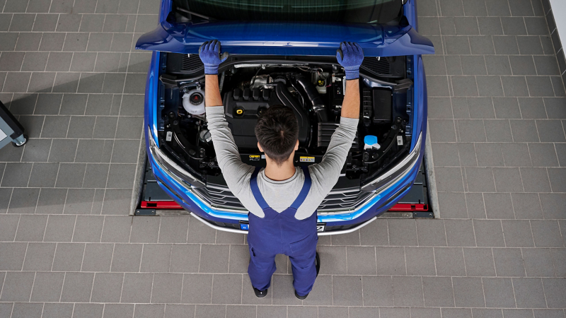 Mechanic looking inside the bonnet of a car at the enginee 