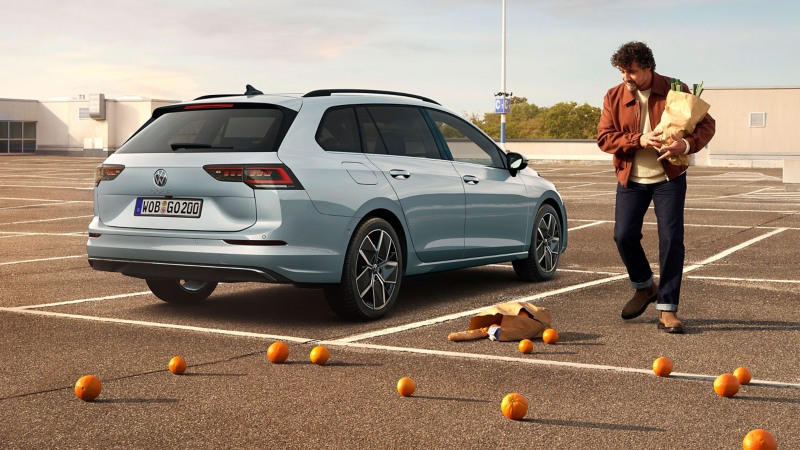 VW Golf Variant auf Parkdeck, daneben Mann mit Einkaufstüte, auf dem Boden kaputte Einkaufstüte und Orangen
