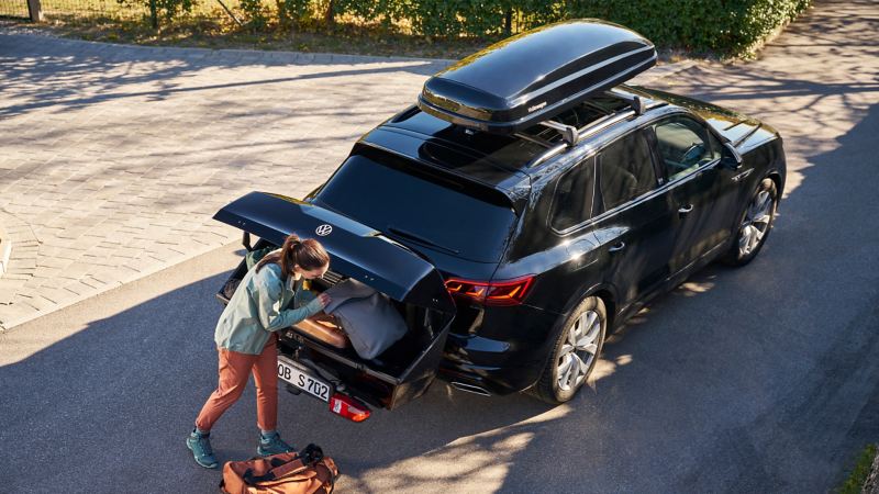 Une femme charge le coffre sur boule d’attelage d'un SUV VW