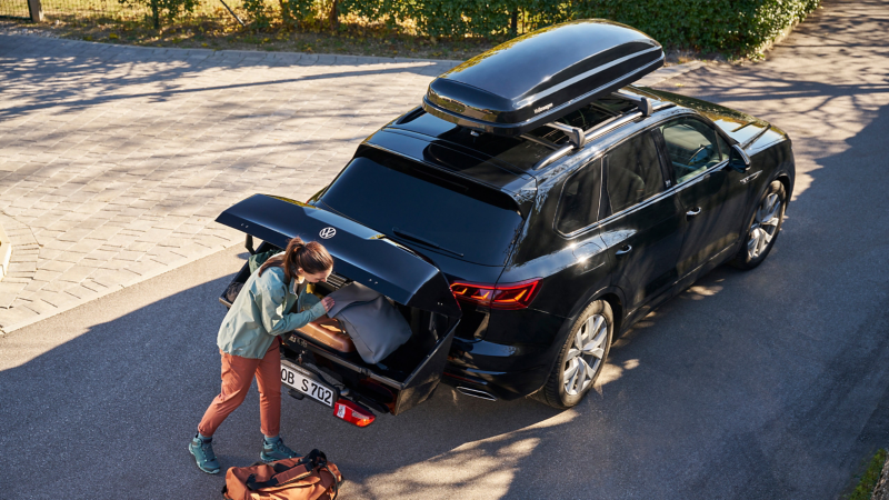 Woman loads rear box of a VW SUV