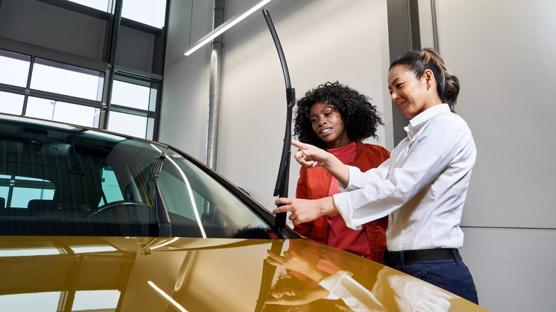 Volkswagen servicemedewerker en klant kijken naar een ruitenwisser