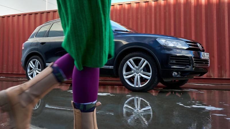 Un VW Touareg 2 con llantas pulidas, mientras en primer plano una mujer atraviesa la imagen 
