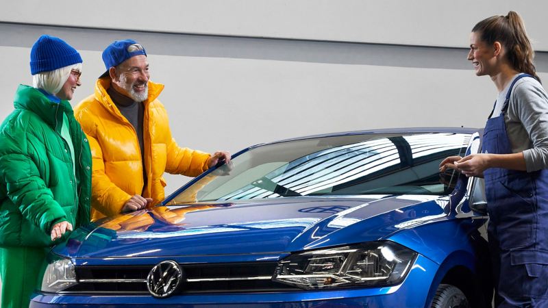 Deux clients échangent avec une technicienne Volkswagen suite à la réparation d'un impact