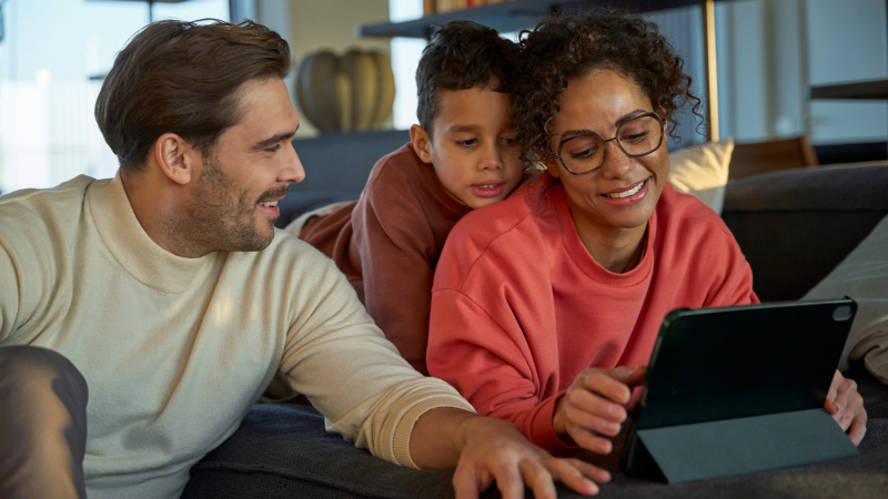 Mutter, Vater und Kind schauen gemeinsam auf ein Tablet