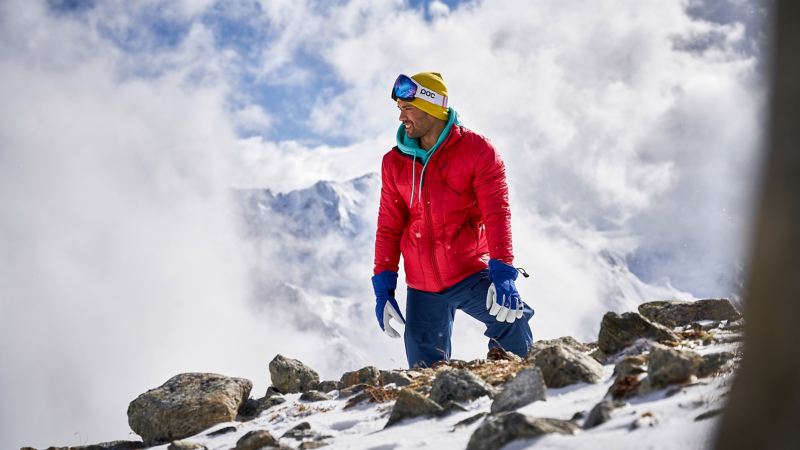 Ein Mann in Skikleidung steht an einem verschneiten Berg