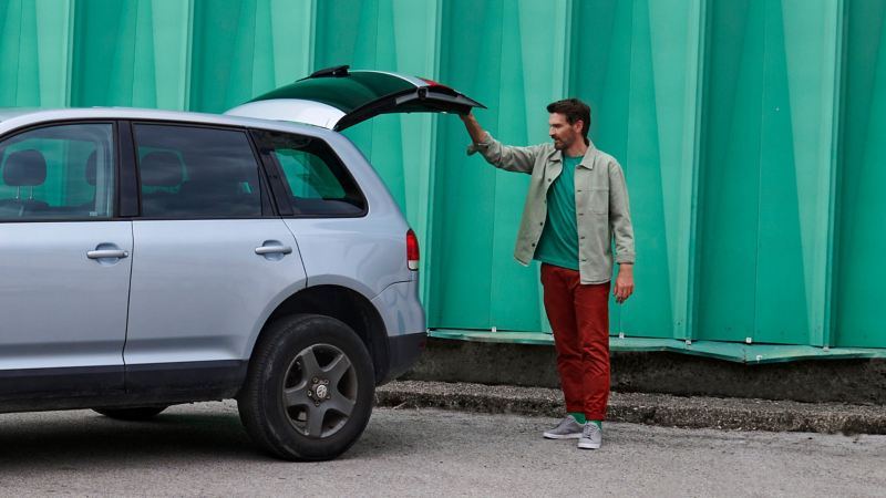 Ein Mann öffnet die Kofferraumklappe seines Touareg 1 mit VW Zubehör