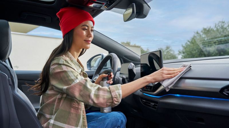 Frau reinigt Innenraum ihres VW Autos mit Pflegemitteln