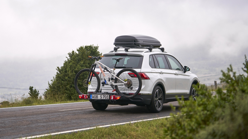 Volkswagen mit VW Dachbox und Fahrradträger fährt auf Straße