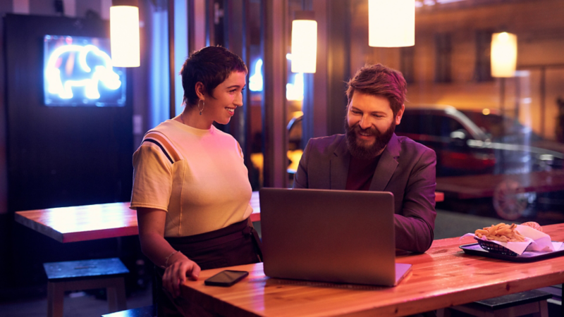 Woman and man stood at desk with laptop open