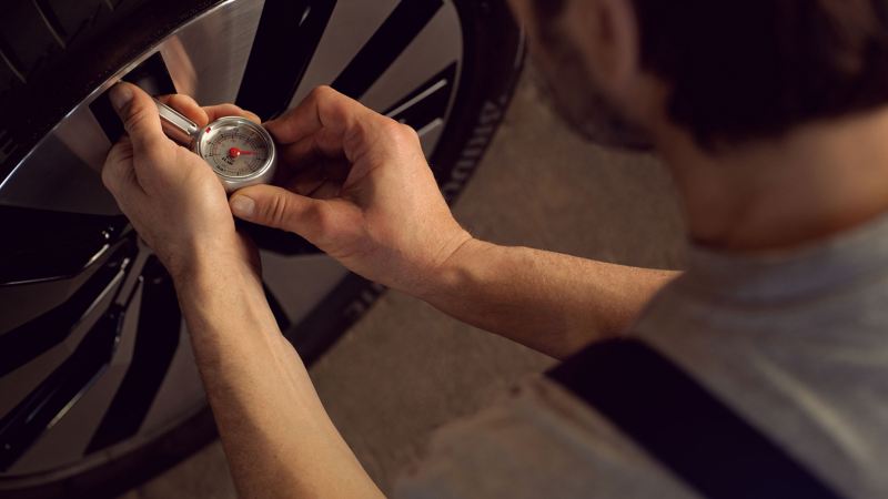 A VW service employee is measuring the tyre pressure