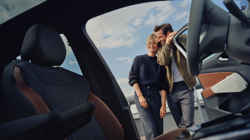A young couple standing at the open door of a VW ID.4.