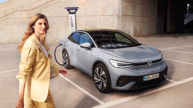 Srebrny ID.5 jest zaparkowany na parkingu. Przed nim przechodzi młoda kobieta. 