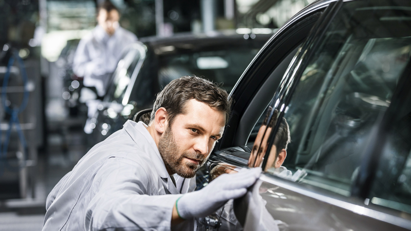 身穿灰衣的技師檢查車側門窗