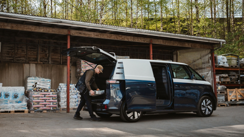 En mann laster varerommet i vw id buzz cargo varebil med jord