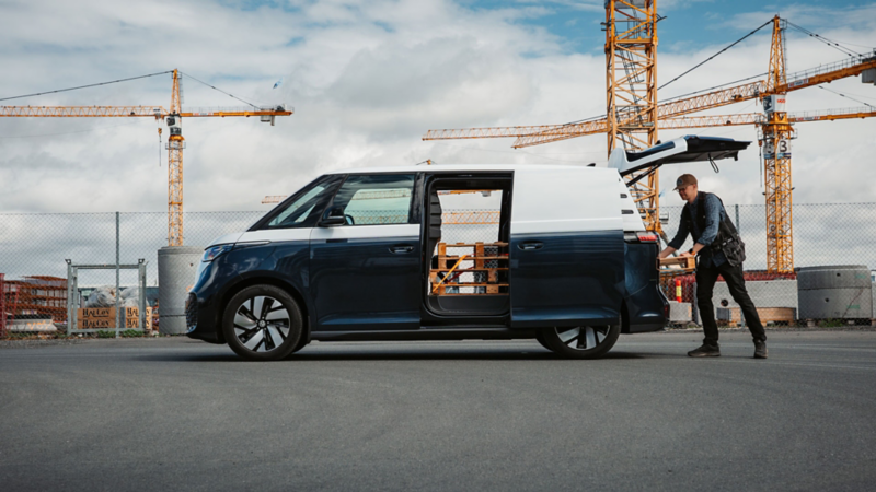 en mann fyller varerommet i vw id buzz cargo varebil med paller på en arbeidsplass